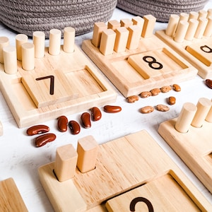 You can use a variety of math counters and math manipulatives with our Little Bud Kids Counting Pegs Math Material. Here, the rectangular cut-out of our number panels allows you to use pebbles, beans, rice, & sand for more number practice.
