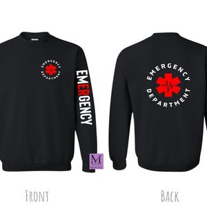 May include: Black long-sleeve sweatshirt with a red and white medical symbol and the text "Emergency Department" on the back. The left sleeve has the word "Emergency" printed vertically in red and white.
