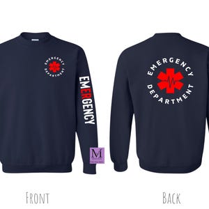 May include: Navy blue long-sleeved sweatshirt with the text "Emergency Department" and a red star of life graphic on the back. The left sleeve has the word "Emergency" printed vertically in white.