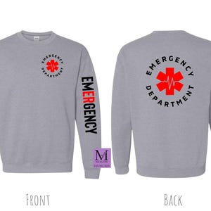 May include: Gray sweatshirt with a red and black star of life graphic on the back and the word "EMERGENCY" printed vertically on the left sleeve. The text on the back reads "EMERGENCY DEPARTMENT".