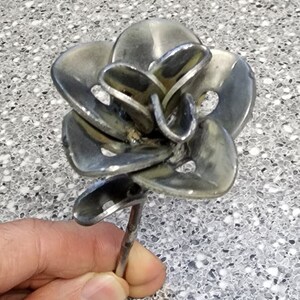 May include: A metal rose sculpture made from recycled metal. The rose is silver in color and has a long stem.