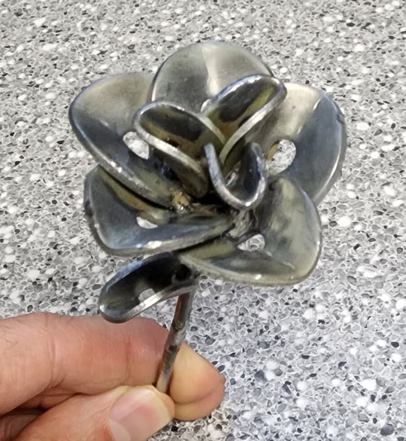 May include: A metal rose sculpture made from recycled metal. The rose is silver in color and has a long stem.