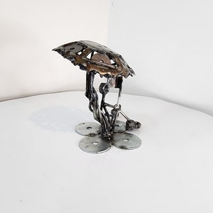 May include: A metal sculpture of a mushroom with a detailed top and a base made of five circular metal pieces.