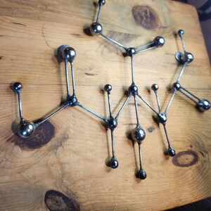 May include: A silver metal sculpture with a geometric design. The sculpture is made up of multiple spheres connected by thin rods. The spheres are all the same size and are evenly spaced apart.