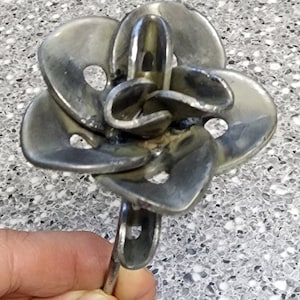 May include: A metal flower sculpture made from recycled metal washers. The flower has a stem and multiple petals with holes in them.