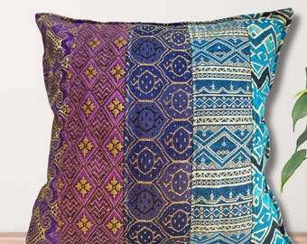 May include: A decorative cushion with a patchwork design featuring purple, blue and gold geometric patterns.