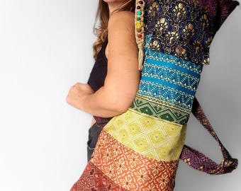 May include: A multi-colored yoga mat bag with a rainbow pattern. The bag is made of different fabrics and has a strap that can be worn over the shoulder.