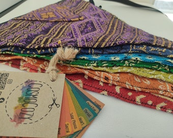 May include: A stack of colorful, patterned fabric bandanas in shades of purple, blue, green, orange, and red. A tag with the text "COSMIC COZY" and a color chart are attached with a safety pin and twine.