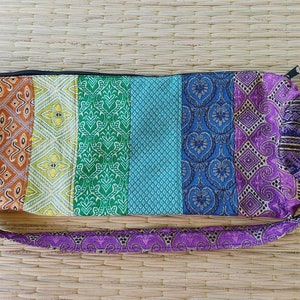 May include: A colourful yoga mat bag with a rainbow pattern. The bag is made of fabric and has a drawstring closure. It is ideal for carrying a yoga mat to and from the studio.