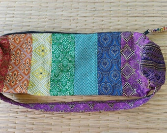 May include: A colorful yoga mat bag with a rainbow pattern. The bag is made of fabric and has a drawstring closure. It is perfect for carrying a yoga mat to and from the studio.