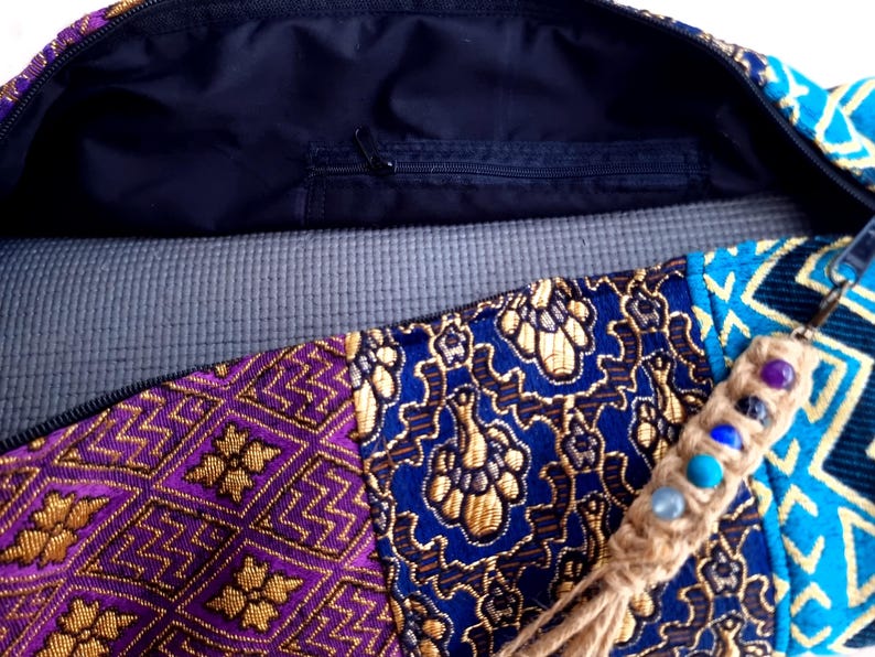 May include: A colorful yoga mat bag with a zippered pocket and a tassel with beads. The bag is made of a patchwork of fabrics with floral and geometric patterns in shades of purple, blue, gold, and turquoise.