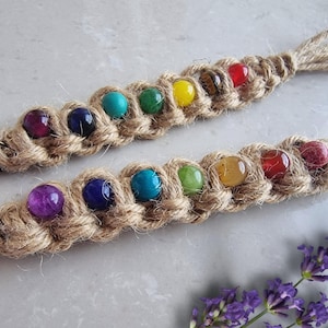 Puede incluir: Un llavero de cuentas de colores arcoíris con un cordón de yute. Las cuentas están enhebradas en un cordón de yute trenzado y tienen un llavero plateado.