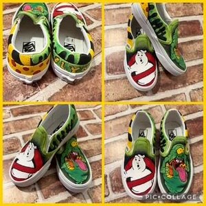May include: Four pairs of custom-painted slip-on trainers. The designs feature Ghostbusters characters and slime patterns in green, white, red, and yellow. The shoes are displayed on a yellow and brown surface.