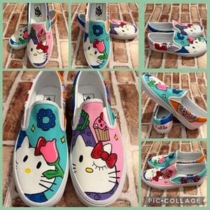 May include: Custom-painted slip-on shoes with a Hello Kitty design. The shoes display white, pink, blue, and red colours, with floral and cupcake accents. The shoes are a size 8.