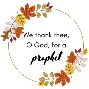 May include: A white background with a gold-colored circular frame. The frame is adorned with autumn leaves in shades of orange, yellow, and brown. The text within the frame reads, "We thank thee, O God, for a prophet."