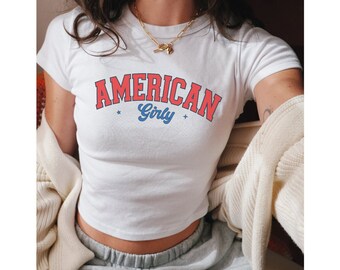 May include: White cropped t-shirt with a red and blue graphic that says "AMERICAN Girly".