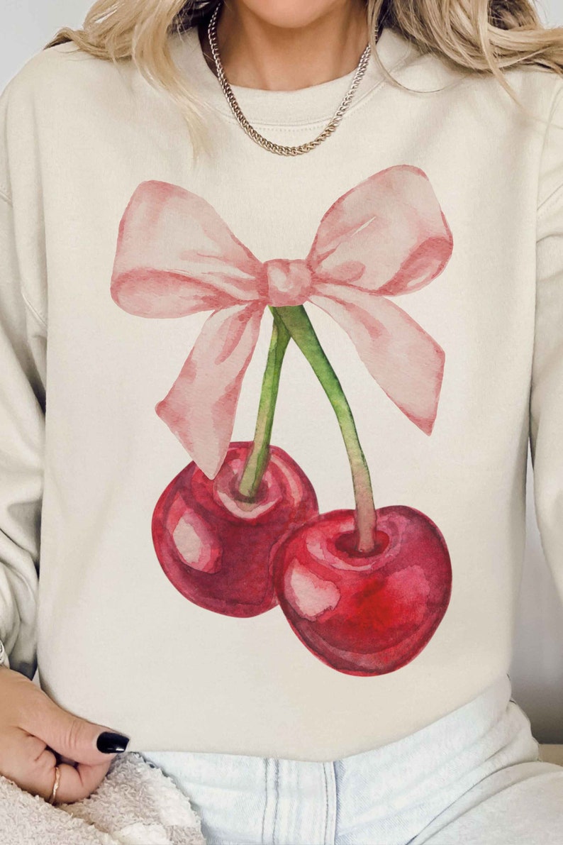 May include: A cream-colored sweatshirt with a watercolor illustration of two red cherries with green stems and a pink bow.