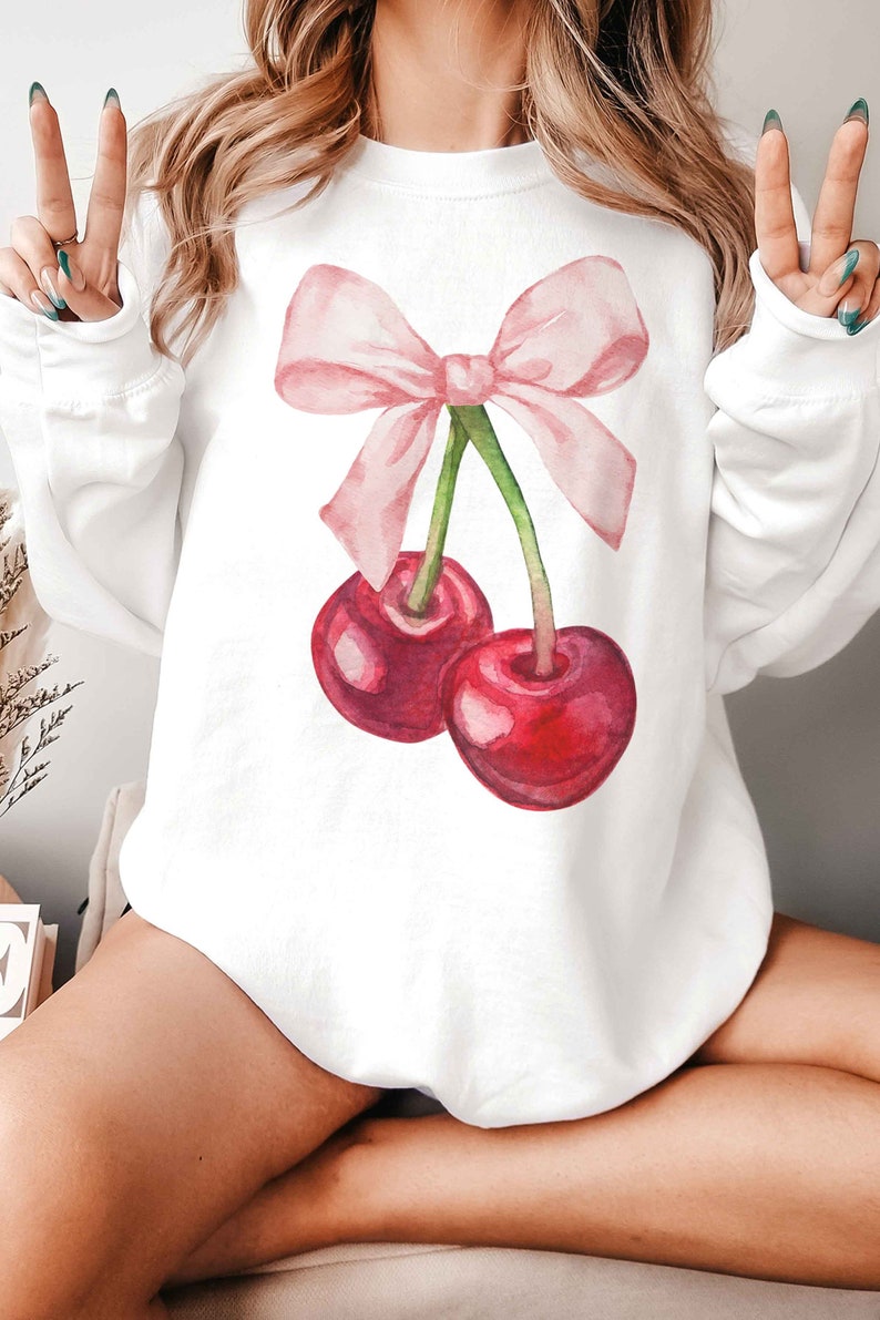 May include: White sweatshirt with a pink bow and two red cherries printed on the front.