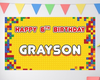 Op de afbeelding: Een gele verjaardagbanner met een Lego-steenpatroon. De banner zegt "Happy 6th Birthday Grayson" in rode en witte letters.