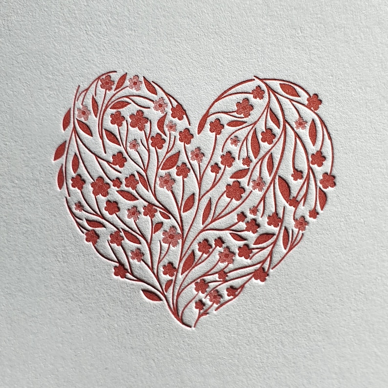Puede incluir: Un dise&ntilde;o en forma de coraz&oacute;n rojo hecho de flores y hojas estilizadas.