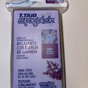 May include: A purple and white bar of soap with a lavender scent. The soap is labeled "T.TAIO esponjabón" and "RELAJANTE CON ESENCIA DE LAVANDA". The soap is labeled "esponja + jabón en 1" and "sponge + soap in one!"