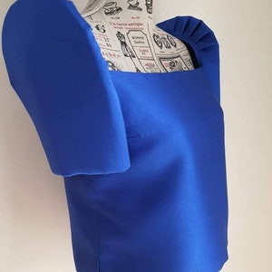 May include: A vibrant blue top with a square neckline and puffed sleeves. The top is made of a smooth, shiny fabric and is displayed on a mannequin. The design features a structured silhouette, showcasing a bold and elegant style.