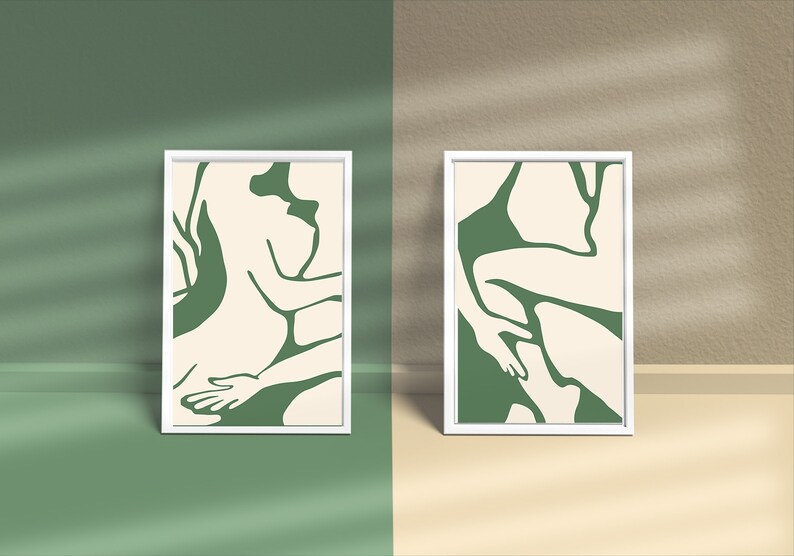 Op de afbeelding: Twee ingelijste prints met abstracte lijntekeningen van figuren in groen en cr&egrave;me kleuren. De prints zijn in witte lijsten en hangen aan een muur.