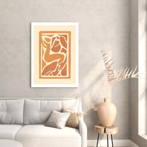 May include: A framed abstract art print with a beige background and a brown silhouette of a person in a stylized pose.