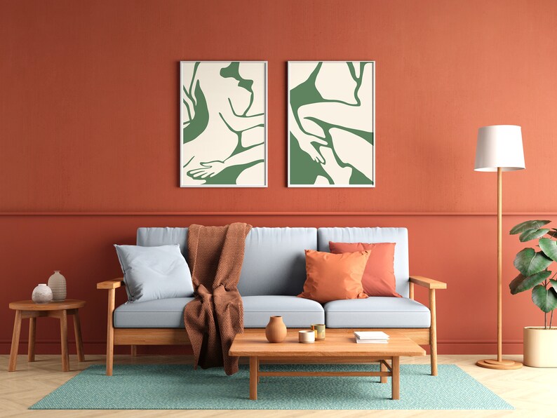 Op de afbeelding: Een woonkamer met een lichtblauwe bank, twee groene abstracte kunstprints, een houten salontafel, een bruin plaid en een staande lamp met een witte kap.