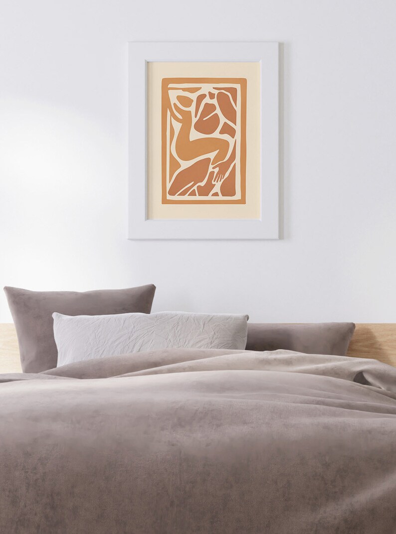 May include: A framed print of an abstract art piece featuring a stylized human figure in shades of orange and brown against a cream background.