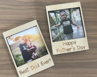 May include: Two wooden photo frames with pictures inside. One frame says "Best Dad Ever!" and shows two children. The other frame says "Happy Father's Day" and shows a child. The frames are made of light-colored wood.