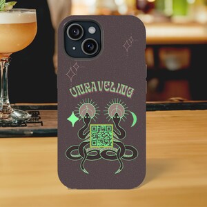 May include: A dark gray phone case with a design of two snakes with their heads facing each other. The snakes are green and have a QR code in the center. The text "UNRAVELING" is above the snakes in a light green color.