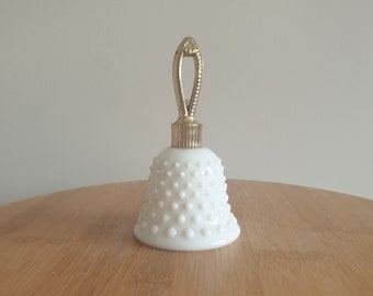 May include: White milk glass bell-shaped perfume bottle with a gold-tone stopper and handle.