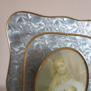 Op de afbeelding: Een gouden fotolijst met een zilveren reli&euml;fpatroon. De lijst bevat een vintage foto van een vrouw die een baby vasthoudt.