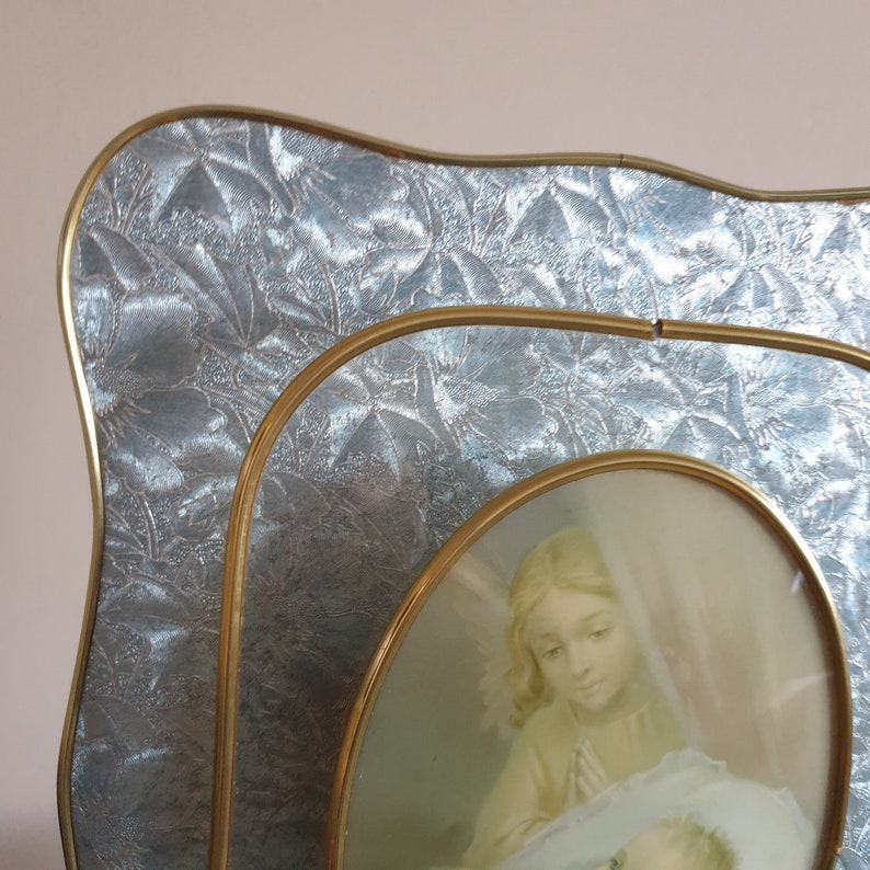 Op de afbeelding: Een gouden fotolijst met een zilveren reli&euml;fpatroon. De lijst bevat een vintage foto van een vrouw die een baby vasthoudt.