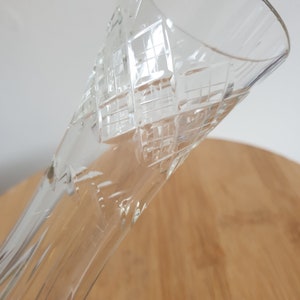 Puede incluir: Un jarr&oacute;n de vidrio transparente con un patr&oacute;n de diamante grabado en la superficie. El jarr&oacute;n es alto y delgado con una abertura acampanada.