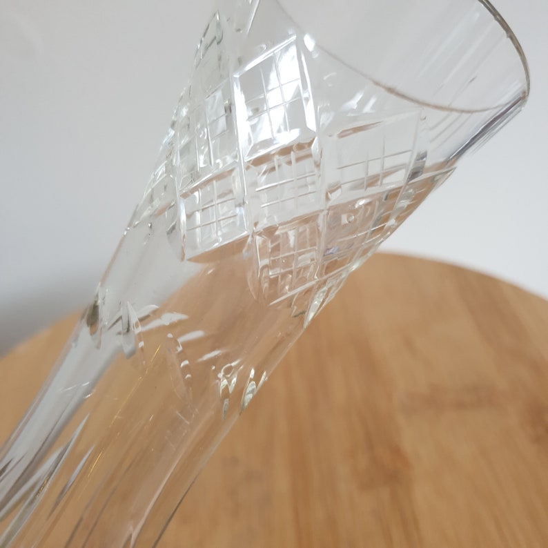 Puede incluir: Un jarr&oacute;n de vidrio transparente con un patr&oacute;n de diamante grabado en la superficie. El jarr&oacute;n es alto y delgado con una abertura acampanada.