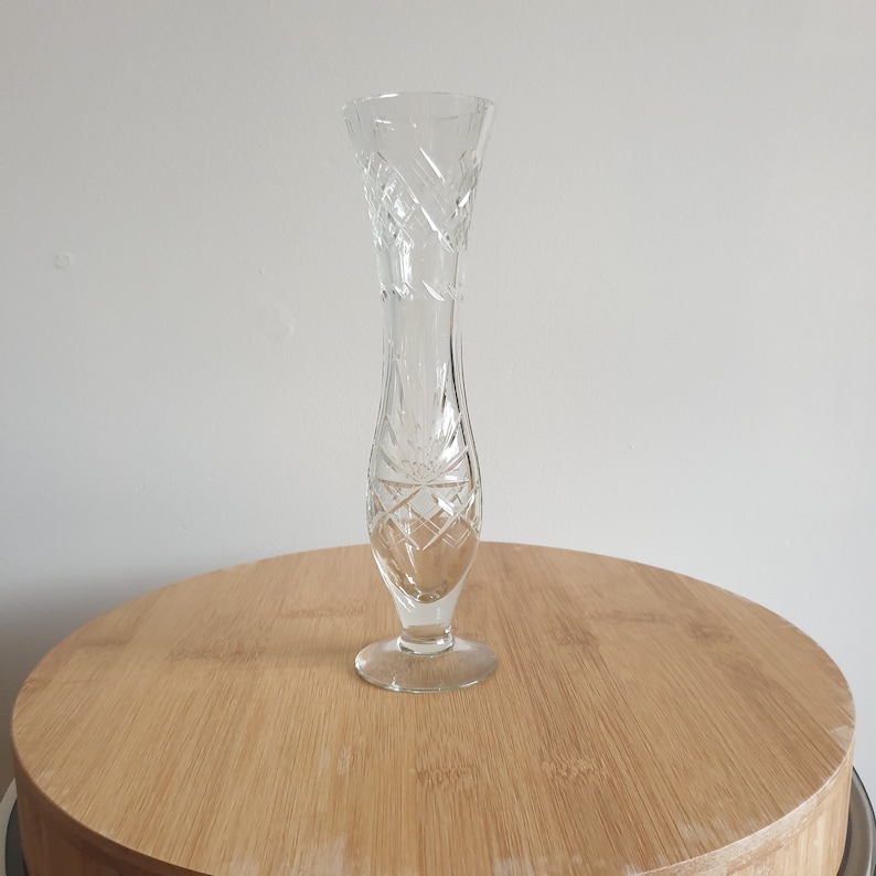 Puede incluir: Un jarr&oacute;n de vidrio transparente con un dise&ntilde;o de vidrio cortado. El jarr&oacute;n tiene una forma alta y esbelta con una abertura acampanada y una base redonda.