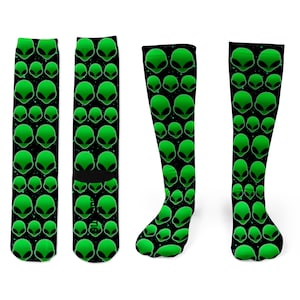 May include: Three pairs of black and green knee-high socks with a repeating pattern of green alien heads on a black background.