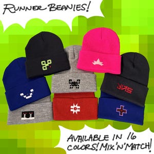 May include: A collection of cuffed beanies in black, blue, grey, red, and hot pink, each featuring unique embroidered pixelated designs. The text RUNNER BEANIES! appears at the top, and AVAILABLE IN 16 COLORS! MIX 'N MATCH! is at the bottom.