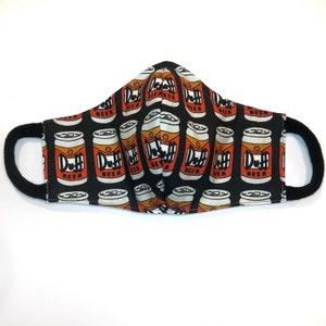 Op de afbeelding: Zwart gezichtsmasker met een herhalend patroon van rode en witte Duff Beer-blikjes. De blikjes hebben de tekst "Duff Beer" erop gedrukt.