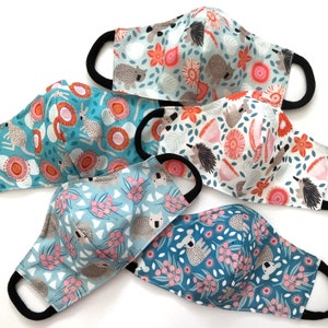 May include: Five different fabric face masks with various patterns. The masks feature a variety of animals and floral designs in shades of blue, pink, and white.