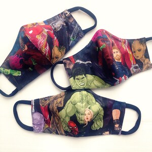 Op de afbeelding: Drie stoffen mondmaskers met verschillende Marvel-personages, waaronder Hulk, Groot en Captain America. De maskers zijn zwart met kleurrijke ontwerpen.