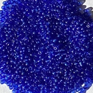 May include: A large pile of small, round, blue glass beads.