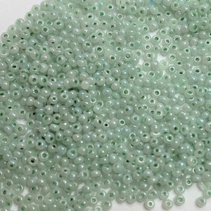 May include: A large pile of small, light green glass beads, with a US dime for scale.