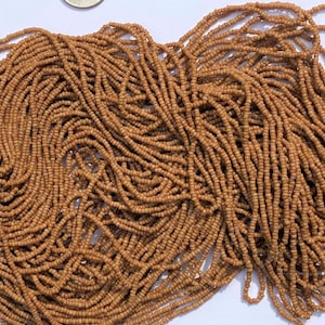 May include: A large pile of brown seed beads, approximately the size of a US dime.