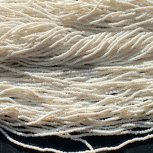 Op de afbeelding: Een close-up van een stapel witte kralen. De kralen zijn klein en rond en zijn in een willekeurig patroon gerangschikt. De kralen zijn van een uniforme witte kleur.