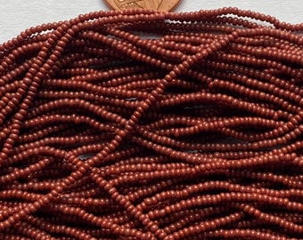 May include: A close-up of a pile of small, round, terracotta-colored beads. The beads are approximately the size of a US penny.