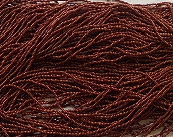 May include: A large quantity of brown seed beads, also known as pony beads, are piled together. The beads are small and round, and they are perfect for crafting.