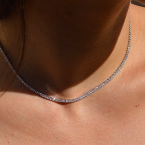 May include: A delicate silver chain necklace with small, clear cubic zirconia stones set in a continuous line.